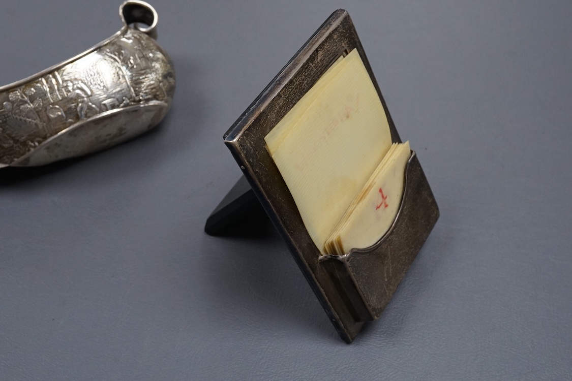 A 1940's silver mounted cigarette box, two small silver dishes, a silver mounted desk calendar, a silver mounted photograph frame and a continental silver bonbon dish modelled as a boat, import marks for John George Pidd